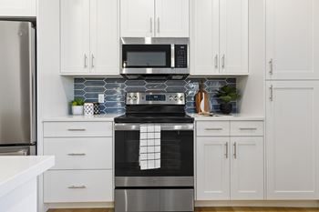 A modern kitchen with white cabinets and stainless steel appliances.
